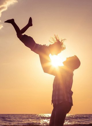 Father and son playing on the beach at sunset